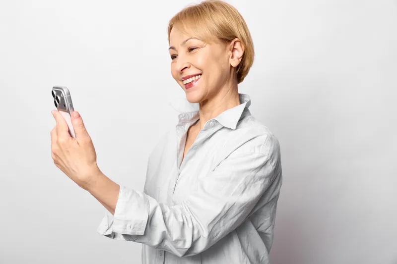 Woman smartphone communication smile healthcare laboratory coat technology, female doctor smiles with phone, telehealth communication in clean studio
