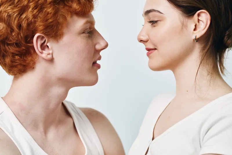 Young man and woman face to face closeup with eyes closed for intimacy connection affection and trust in studio with simple background. Portrait of couple in casual wear.