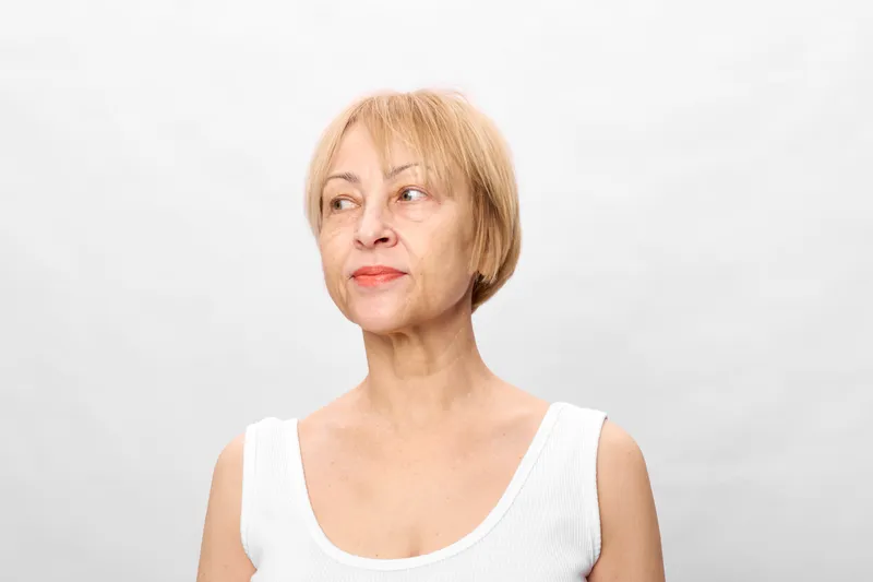Elderly woman portrait, senior blonde studio health white age wellness, calm headshot, white background, natural skin texture, minimalist composition, neutral gaze