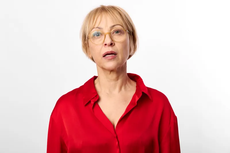 Woman with glasses, short hair, red shirt, studio portrait on white background, surprised expression, soft even lighting, neutral pose, concept of communication attention and surprise