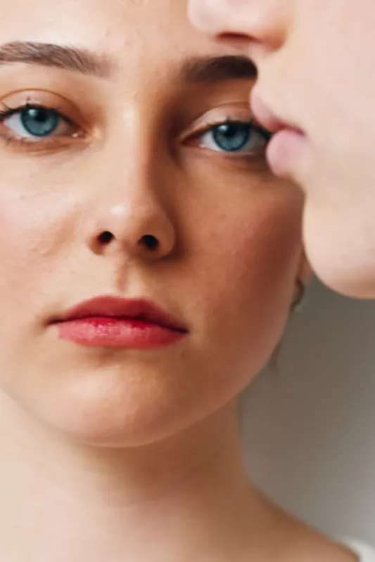 Closeup of young woman face with blue eyes red lips and smooth skin natural beauty and serious expression with soft light on neutral background portrait.