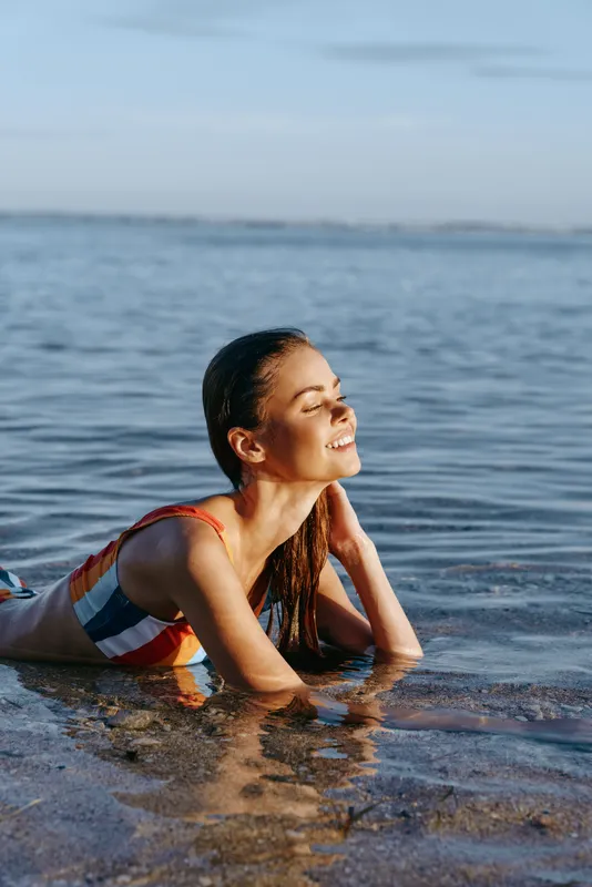 Woman, beach, sea, water, summer, relax, smiling, sunlight, calm, outdoors, young woman in shallow ocean, wet hair by shoulders, quiet morning by shoreline, serene mood