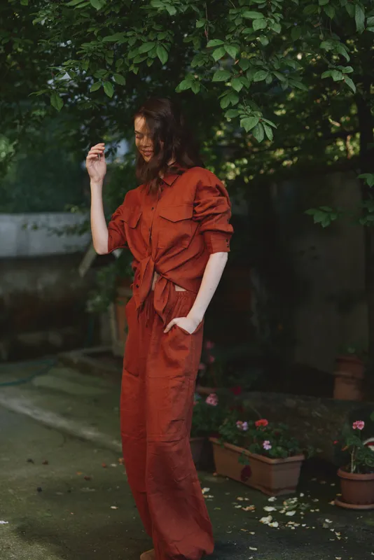 Candid woman outdoors in an orange dress, relaxed pose among lush greenery, soft light, natural colors, lifestyle moment