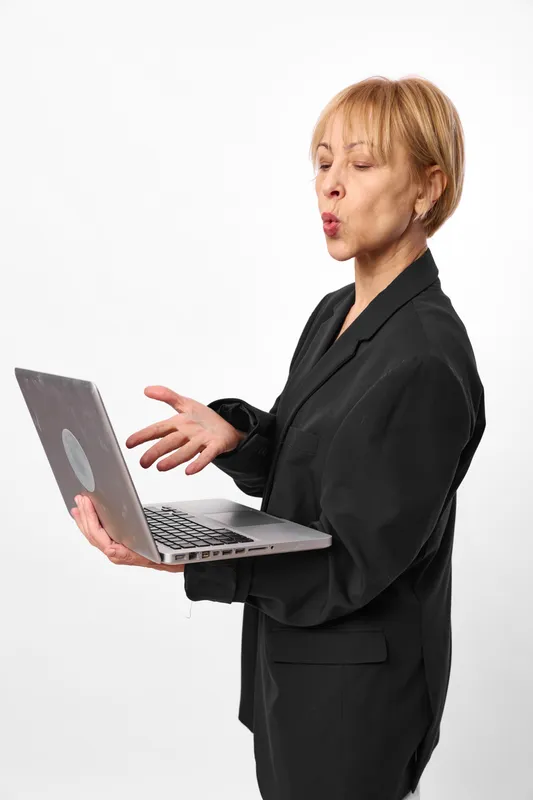 Woman business suit laptop computer office communication isolated studio gesture, open palms, turned toward screen, focused expression, minimal white background, bright light