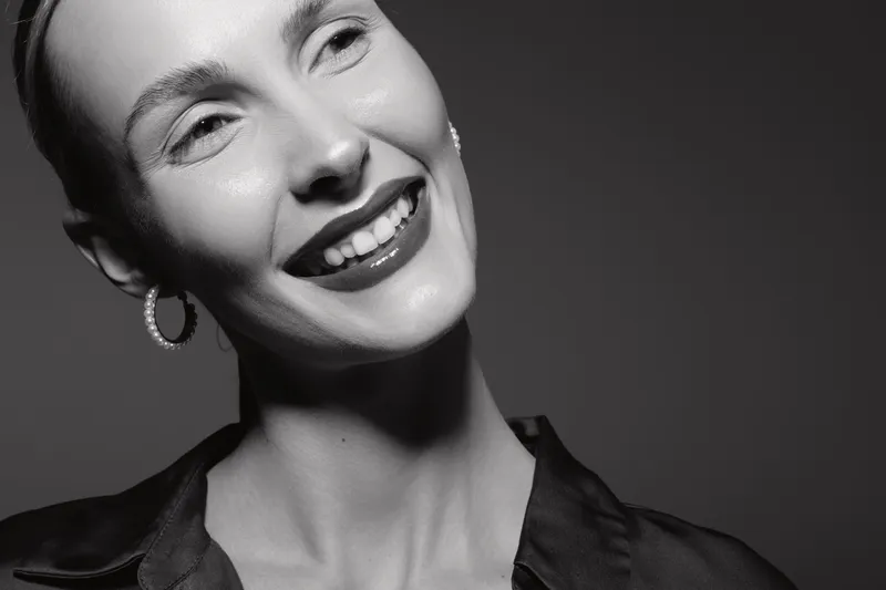 Smiling white woman with pale skin and short hair looking to side in black and white portrait. Concept of happiness, confidence, and elegant female beauty.