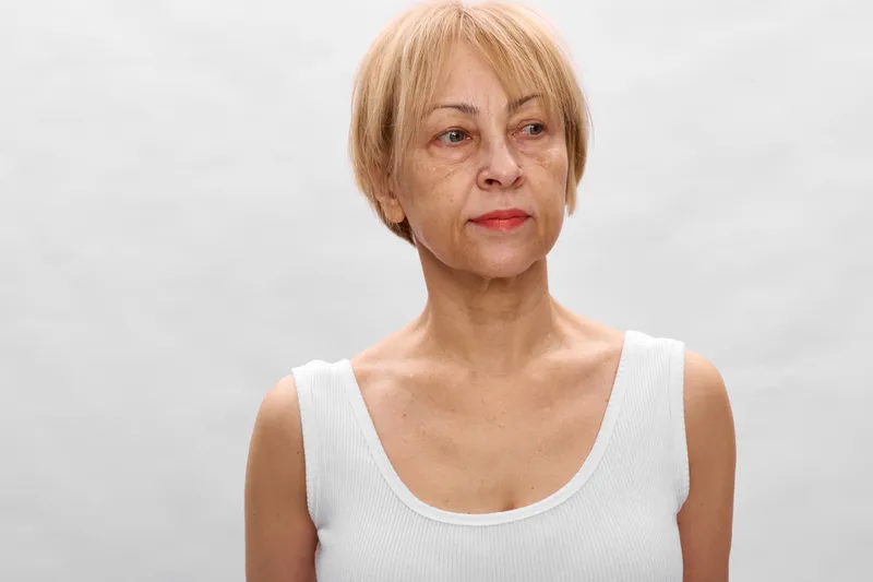 Senior woman portrait with short blonde hair and calm expression, studio background, close up on face, neutral lighting for health and wellness, self confidence concept