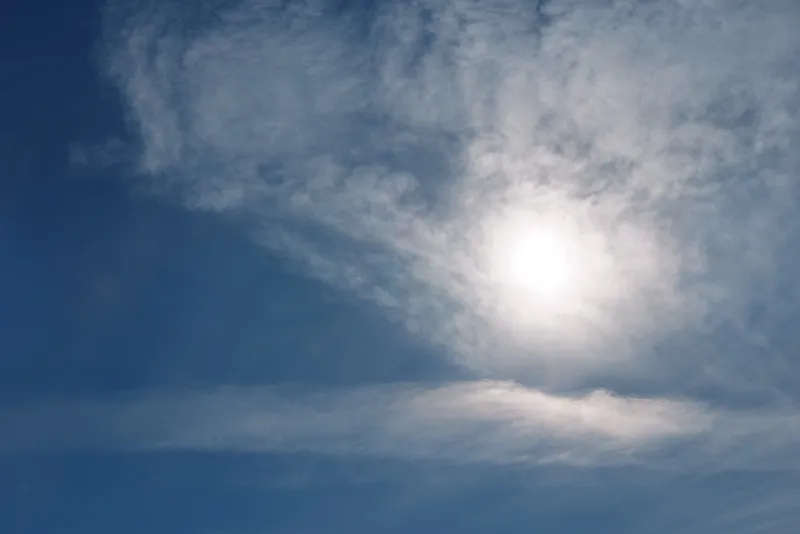 Clear daytime sky with a bright sun and wispy clouds, blue horizon and tranquil weather, natural light for nature, outdoor or atmospheric projects