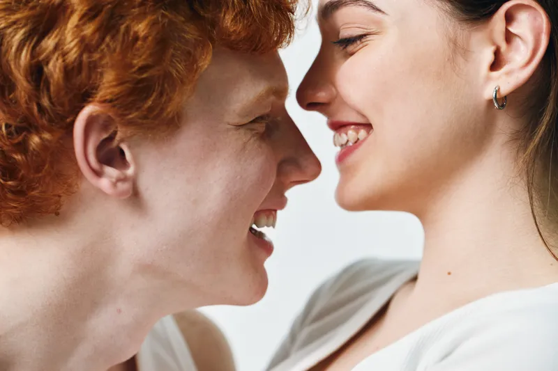 Couple, face to face and smiling with close connection for love, intimacy and happiness. Young man and woman with joyful emotions and affectionate gesture in bright studio lighting.