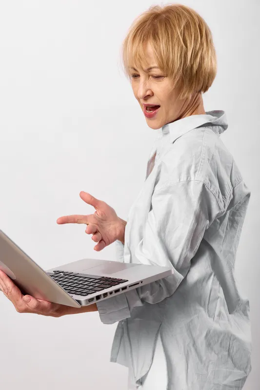 Woman using laptop in a studio, side view, hands gesturing while communicating, office business concept of remote work, neutral background, soft light