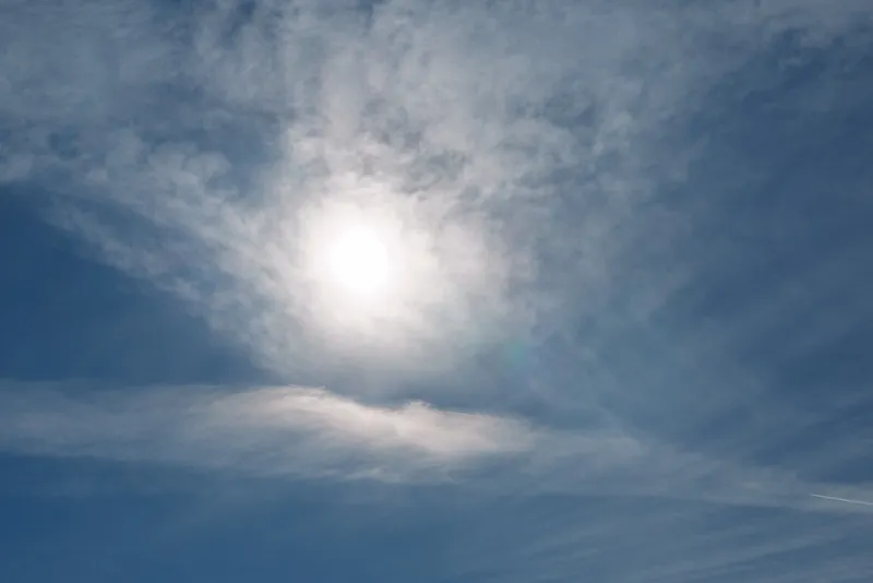 Clear blue sky with a bright sun and wispy clouds, daytime illumination highlighting natural light and a calm atmosphere for outdoor photography.
