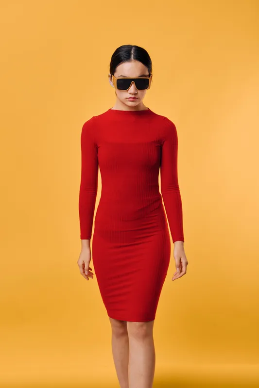 Woman in red dress and sunglasses posing on yellow background fashion style casual look confident model standing in studio with modern outfit and minimalist atmosphere.