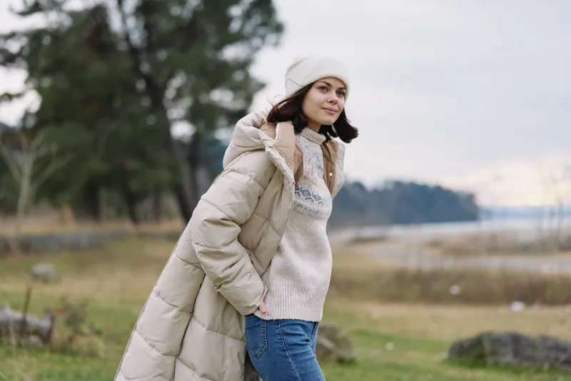 Winter fashion, outdoor portrait, cozy clothing with an oversized coat and beanie beside a lake, casual style for cold weather, serene natural backdrop and expansive landscape