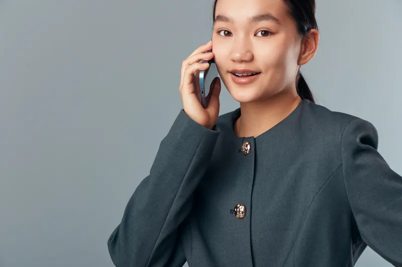 Woman talking on phone with smile and business jacket, casual communication and mobile connection for technology and modern lifestyle in studio background.