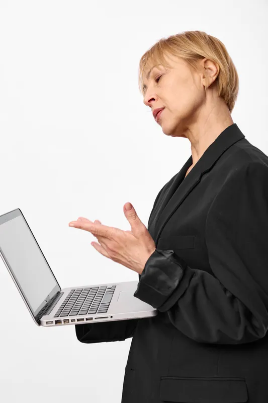Woman laptop business communication office technology consulting work adult in dark suit, side profile, focused expression, typing on laptop, soft studio lighting, calm serious mood