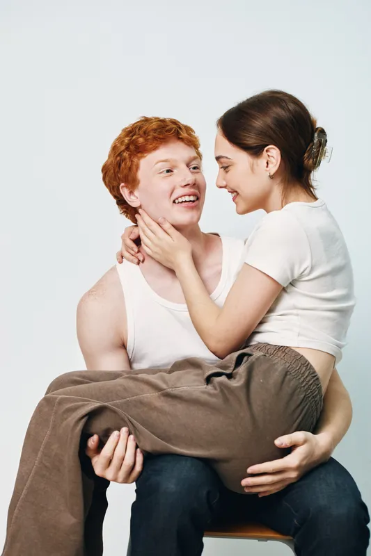 Young couple, woman and man smiling and looking at each other, holding with care and affection in casual clothes on white background, happiness and love together