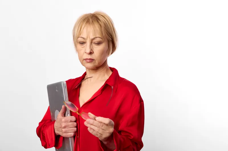 Woman senior portrait holding a smartphone in a red shirt, studio white background, hands and face focused, technology and communication concept, soft studio light