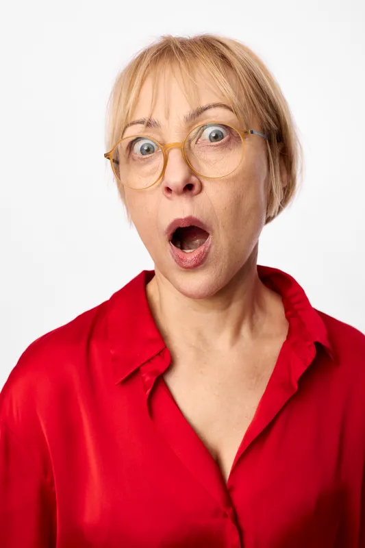woman glasses surprised blonde portrait studio red expression face emotion shock, closeup headshot on white background, startled reaction, studio lighting, modern fashion