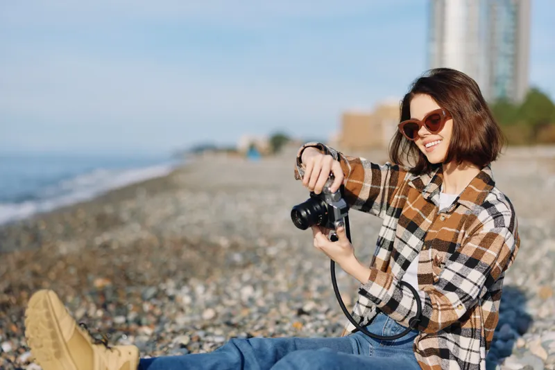 beach photography camera woman casual outdoors portrait lifestyle seashore shoreline sunny lens equipment traveler travel vacation nature summer relaxed candid fashion scene scenic joy creative mood