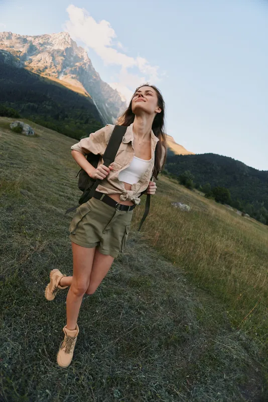 A woman hiking in the mountains with a backpack, outdoors and nature in a wide valley, enjoying the fresh air. Concept for active lifestyle and adventure.