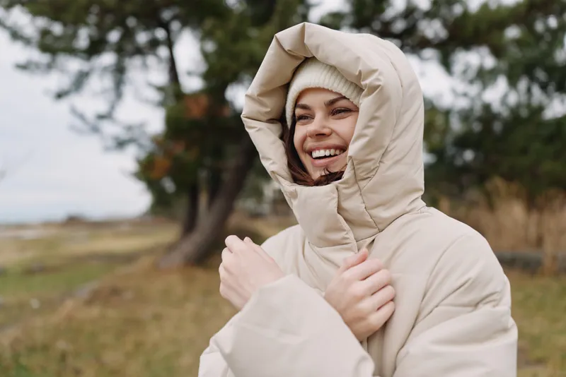 Coat, outdoor, hood, smiling, cold, weather, autumn, jacket, person, nature, landscape with trees and open field, casual fashion and cozy outerwear for chilly days spent outside in broad daylight