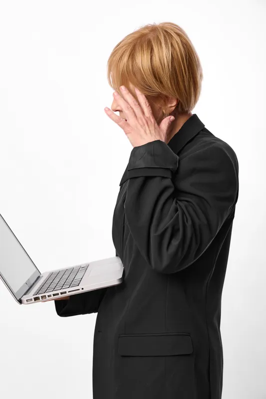Woman with laptop, business suit, hand covering mouth, shy stressed expression, standing in minimal studio, white background, looking at screen, quiet mood