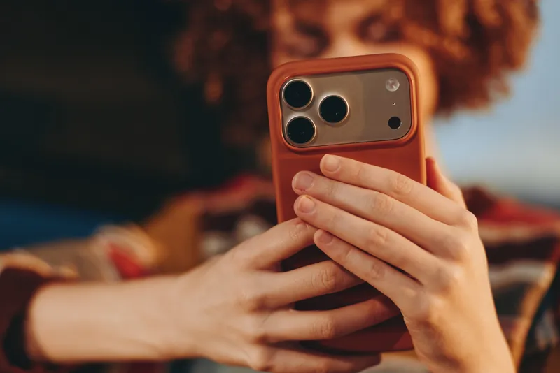 Woman hands smartphone portrait lifestyle at home, relaxed close up in warm studio light, blurred sofa background, using phone for communication and social media, soft joyful mood.