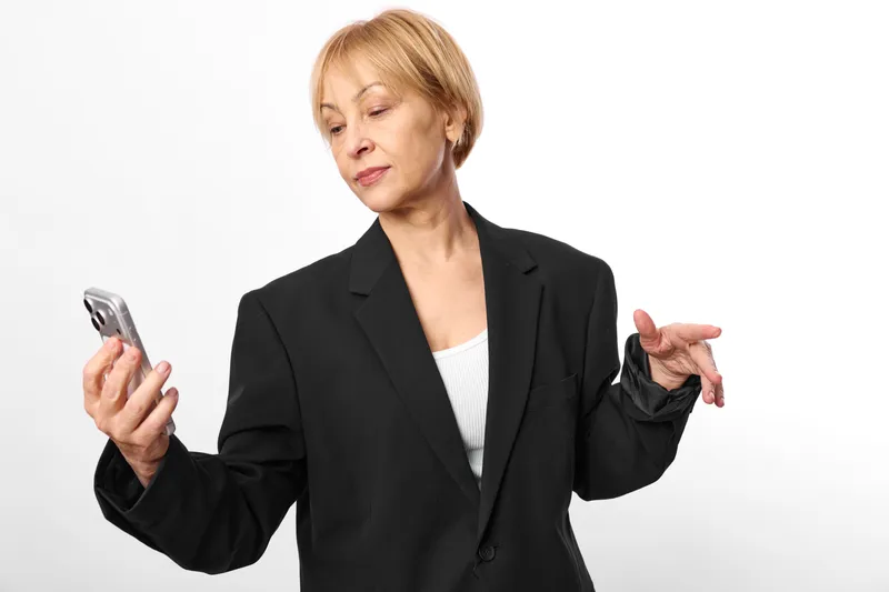 Woman older business smartphone phone communication gesture isolated on white studio, holding mobile in hand, explaining uncertainty with open palms, businesswoman portrait