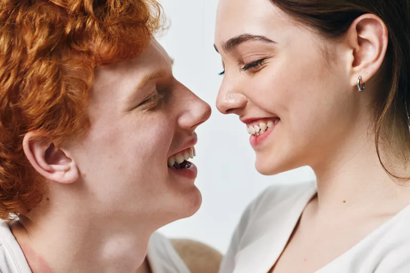 Young couple smiling face to face with happy expressions, closeup portrait of man and woman enjoying moment with affection and love on light background.