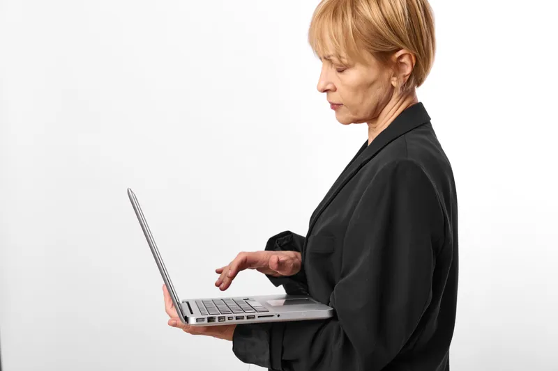 Woman with laptop typing in studio, business office side profile, focused expression, clean white background, modern technology, professional communication, copy area
