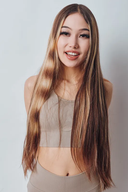 Young woman with long straight hair posing smiling in casual top against white background for beauty, fashion, and lifestyle concept with natural look and confidence.