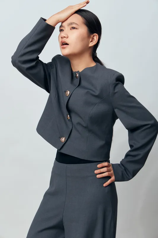 Woman in gray business suit posing and looking far away with hand on forehead. Studio portrait, confident female model with neat hairstyle on white background.