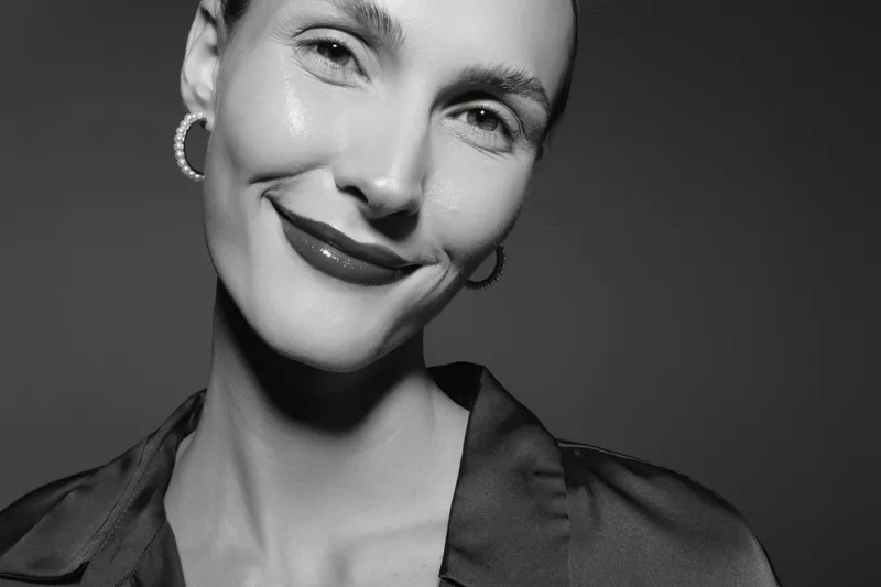 Smiling white woman with pale skin and short hair in black satin blouse. Close-up portrait with earrings in black and white. Concept for beauty and confidence.