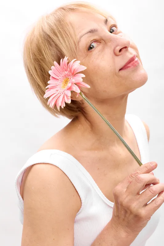 woman flower portrait spring beauty studio skincare freshness pink blossom, woman holding a pink flower near face, white background, soft light, calm elegant expression, closeup