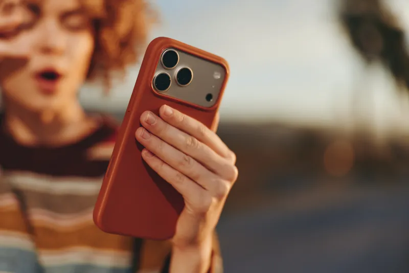 Woman lifestyle, holding a smartphone, outdoors at sunset, communication and technology in focus, her portrait framed by warm light, blurred park background and calm mood
