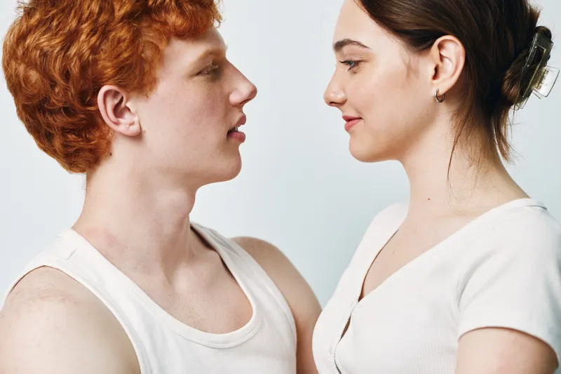 Young man and woman facing each other, closeup portrait with neutral background in casual clothing. Interaction, connection, relationship and communication concept with two people.