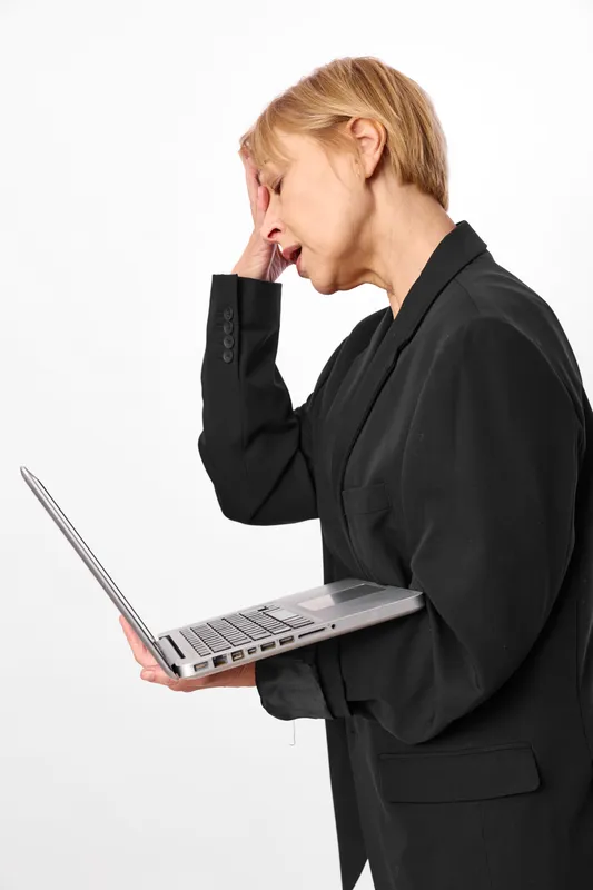 Business woman in black suit, holding laptop, side profile, touching ear, thoughtful stress mood, white studio background, quiet calm soft lighting, concentrated on work