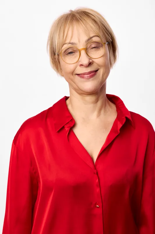 Senior woman portrait, wearing glasses and a red shirt, smiling in a studio against a white background, calm confidence, concept of aging, maturity
