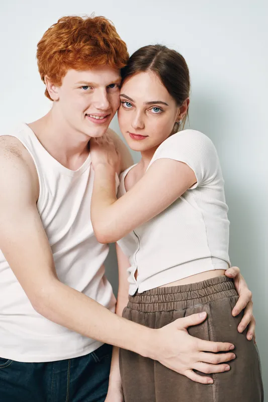 Couple, young man and woman embracing and posing indoors, closeup portrait with natural expressions wearing casual clothes against white background in studio.