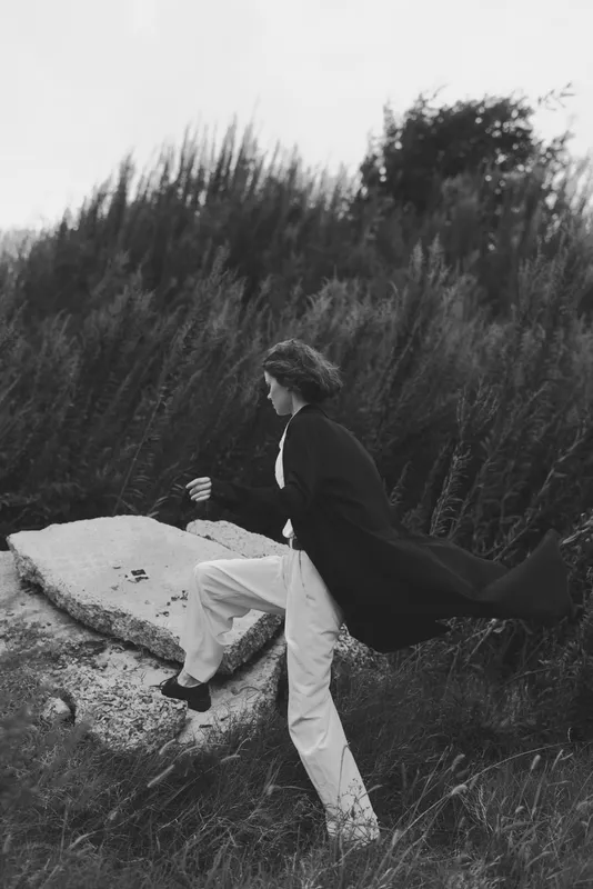 Cape fluttering behind, runner on a rocky outcrop in a windy outdoor landscape, dynamic motion and dramatic mood for adventure and freedom