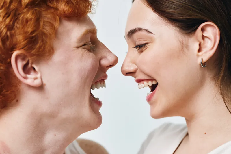 Young man and woman laughing together closeup, happy joyful expressions, faces side by side, smiling people with positive emotions and friendly interaction studio portrait.