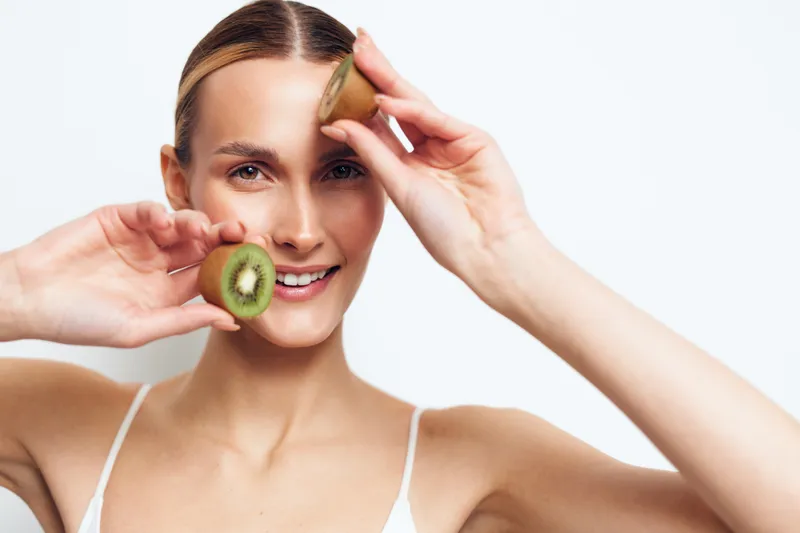 Woman holds an apple and smiles in close up portrait showing healthy eating diet wellness nutrition and fresh beauty suggesting a clean lifestyle and skincare routine