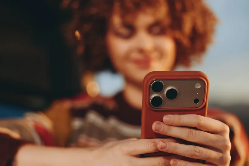 Woman with curly hair holding smartphone, closeup on hands, outdoors at sunset, blurred background, candid selfie, modern technology, lifestyle and relaxation, soft bokeh lights, today
