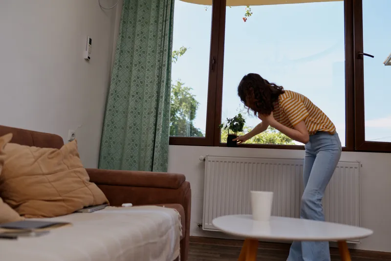 woman lifestyle home interior livingroom plant window light casual cozy scene indoors with natural daylight capturing a relaxed domestic moment in a bright living space
