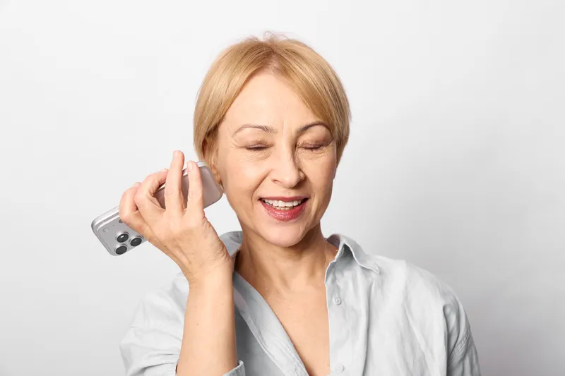 woman phone call smiling elderly communication indoors white portrait headshot female using smartphone talking listening relaxed friendly calm studio background