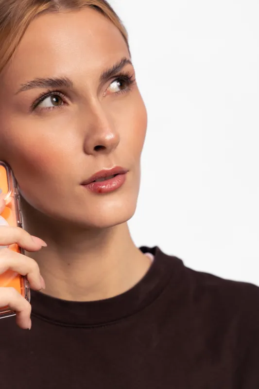 Portrait of a young woman holding a smartphone near her ear looking thoughtfully to the side. Concept of communication, technology, and casual lifestyle with natural expression.