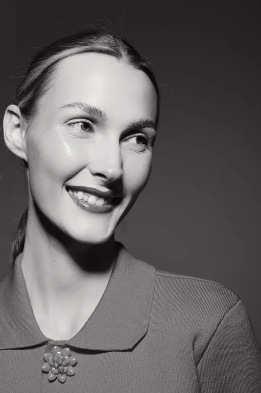 Smiling Caucasian woman with light skin and slicked hair looks aside in black and white studio portrait. Concept of happiness, female beauty, and natural expression.