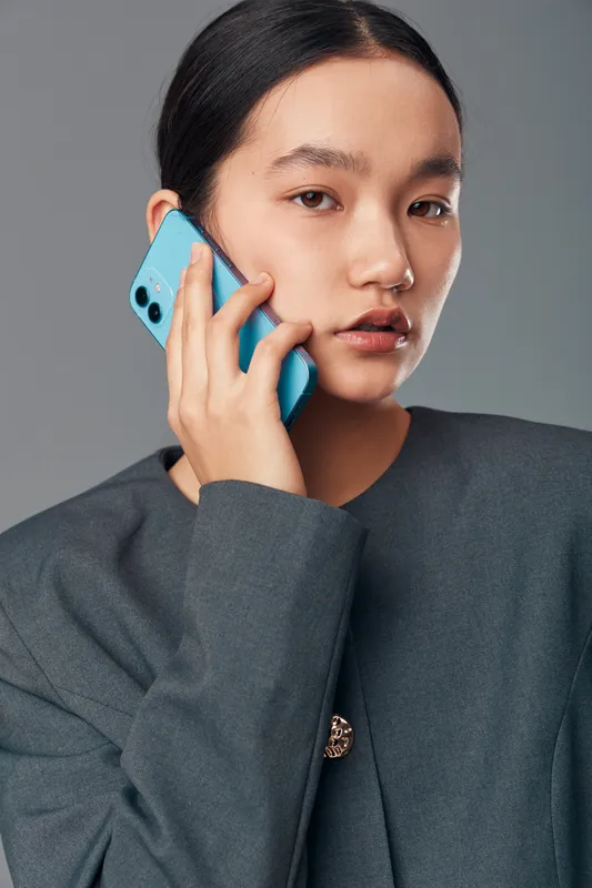 Young woman, portrait and closeup with smartphone on ear for communication, technology and connection. Female talking on phone, casual style in studio with neutral background for lifestyle and modern