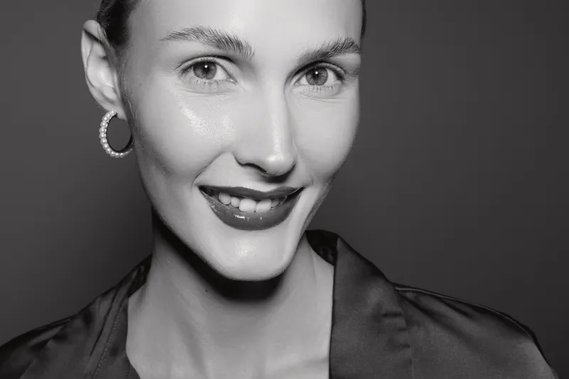 Close up portrait of smiling white woman with fair skin and hoop earrings in studio, natural beauty and confident look.