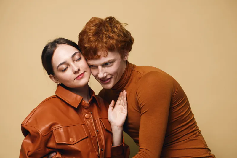 Couple, affection, love, emotions and closeness with young woman and man hugging in warm clothes studio portrait. Intimate, relationship and connection with casual fashion and caring moment.