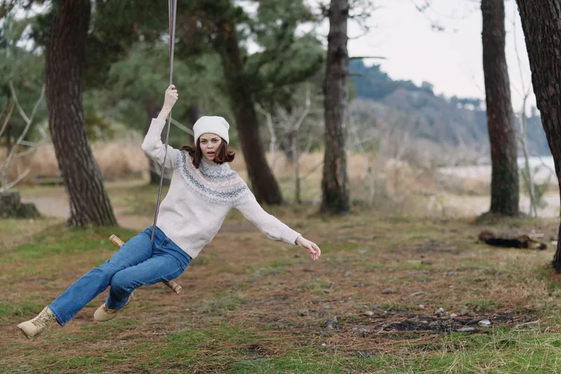 Swing, girl outdoors in a forest setting, playful and carefree as she glides on a rope seat among trees, capturing motion, joy, and a moment in nature.